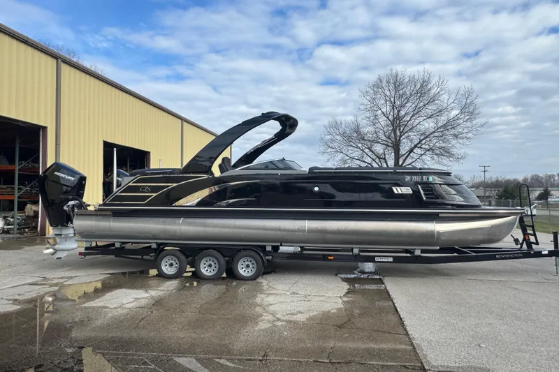 Slide: The Image of 2023 Bennington 30 QXFBAX2 pontoon boat on trailer, parked outside warehouse. - 2
