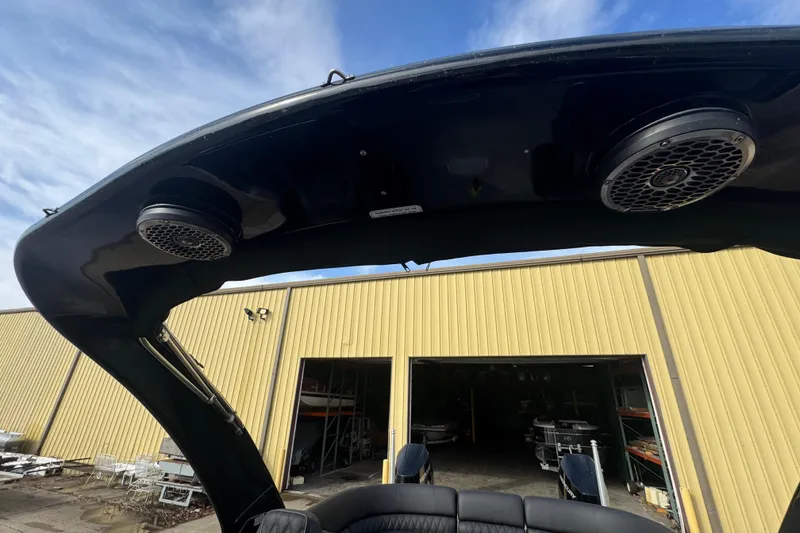 Slide: The Image of 2023 Bennington 30 QXFBAX2 boat with speakers, viewed from below, near a yellow building. - 33