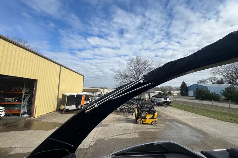 Slide: The Image of 2023 Bennington 30 QXFBAX2 boat with canopy, parked near a yellow warehouse under a cloudy sky. - 35