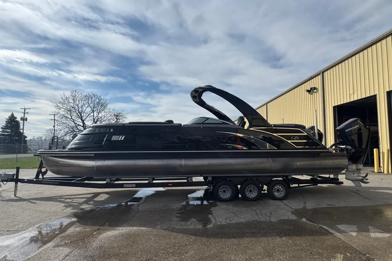 Slide: The Image of 2023 Bennington 30 QXFBAX2 pontoon boat on trailer, parked outside a warehouse. - 7