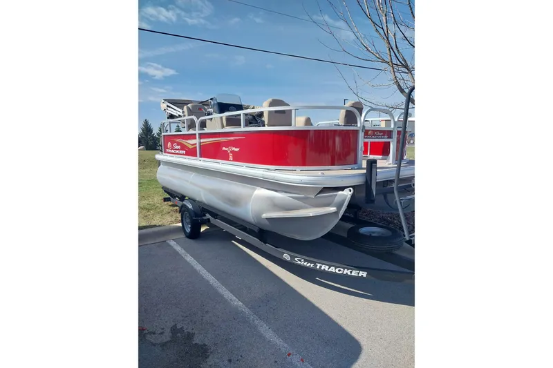 Slide: The Image of 2025 Sun Tracker Bass Buggy 16 DLX pontoon boat on trailer, parked outdoors. - 5