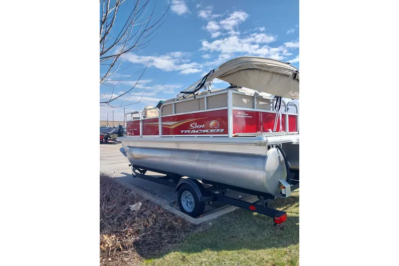Slide: The Image of 2025 Sun Tracker Bass Buggy 16 DLX pontoon boat on trailer, parked outdoors. - 8