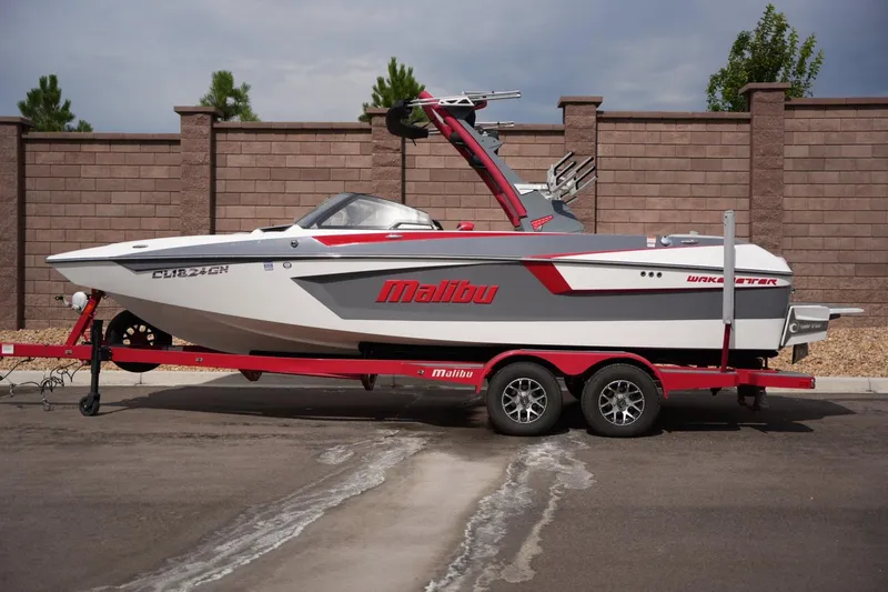 The Image of 2022 Malibu Wakesetter 23 MXZ boat on a red trailer, parked outdoors. - 1