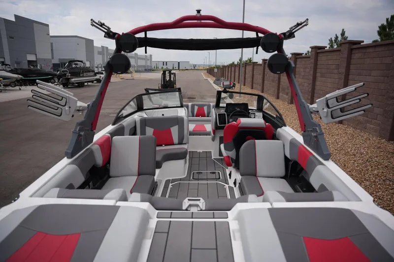 Slide: The Image of 2022 Malibu Wakesetter 23 MXZ boat interior with red and gray seating, docked outdoors. - 17