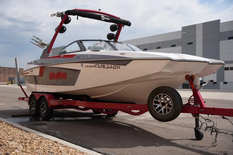Slide: The Image of 2022 Malibu Wakesetter 23 MXZ boat on red trailer, parked outdoors. - 6