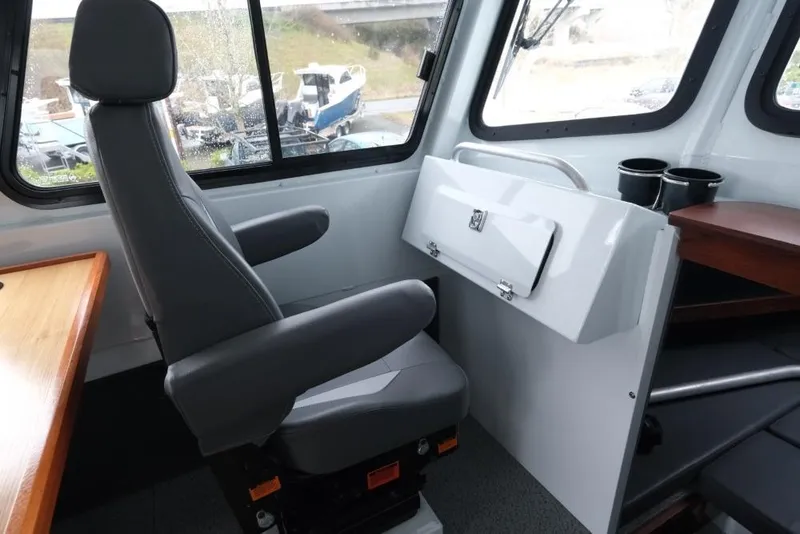 Slide: The Image of 2024 Hewescraft 270 Pacific Explorer ET Hardtop interior with captain's chair and window view. - 16