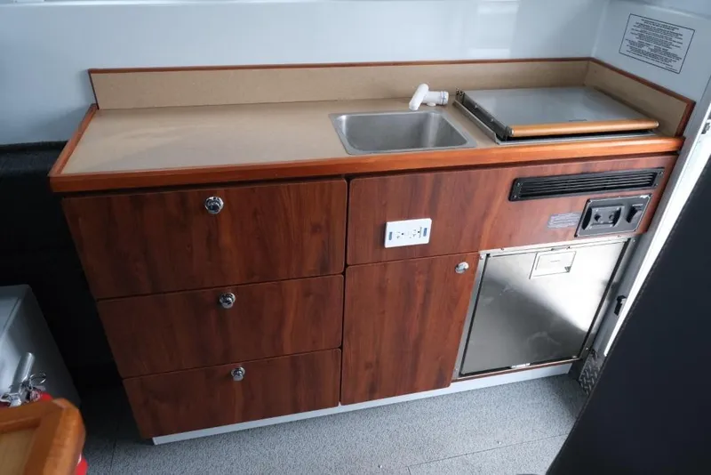 Slide: The Image of 2024 Hewescraft 270 Pacific Explorer ET Hardtop interior kitchenette with sink and storage. - 17