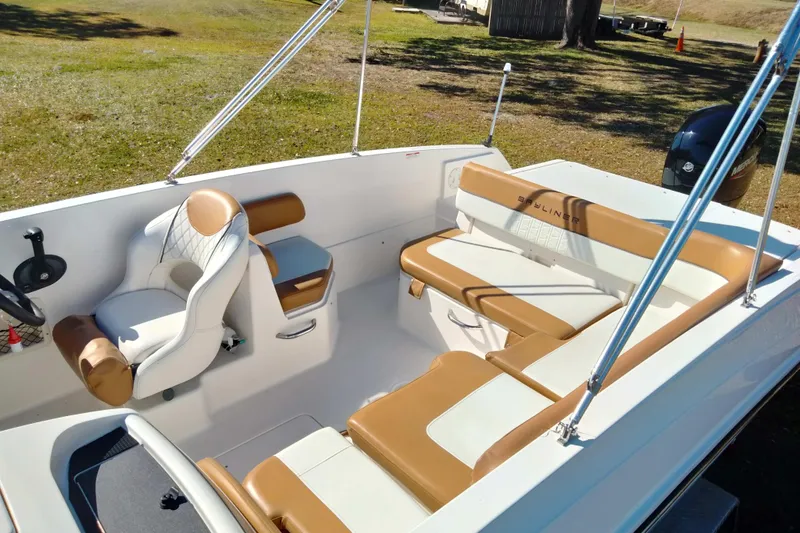 Slide: The Image of 2022 Bayliner VR6 Bowrider OB interior with tan and white seating, steering wheel, and open deck. - 10