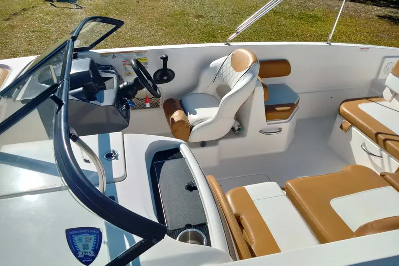Slide: The Image of 2022 Bayliner VR6 Bowrider OB interior with tan and white seating, steering wheel, and dashboard. - 11