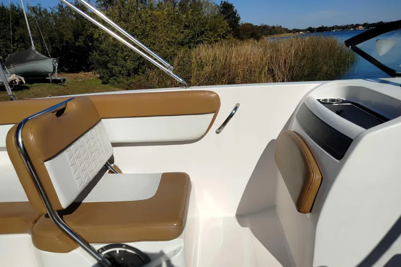 Slide: The Image of 2022 Bayliner VR6 Bowrider OB interior with tan and white seating, near a serene lake. - 17
