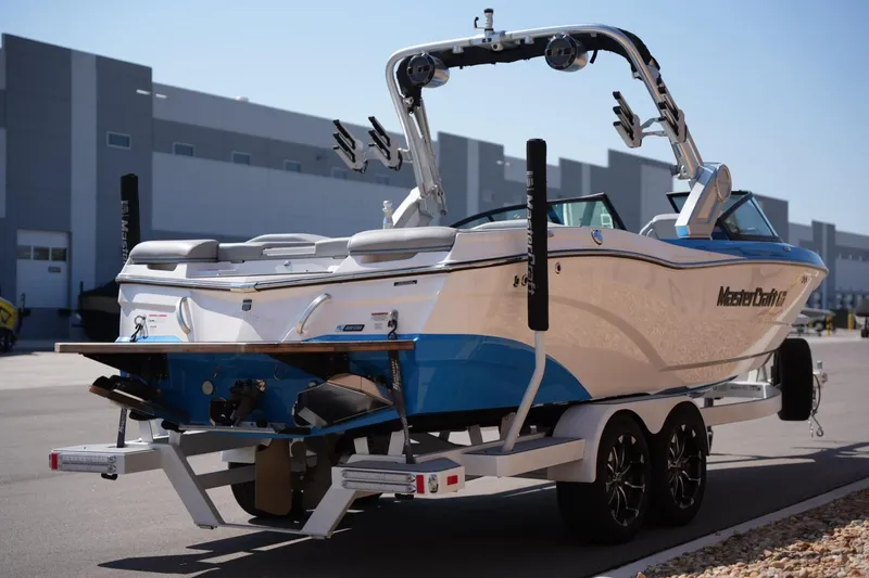Slide: The Image of 2021 MasterCraft XT25 boat on trailer, parked outdoors near industrial buildings. - 4