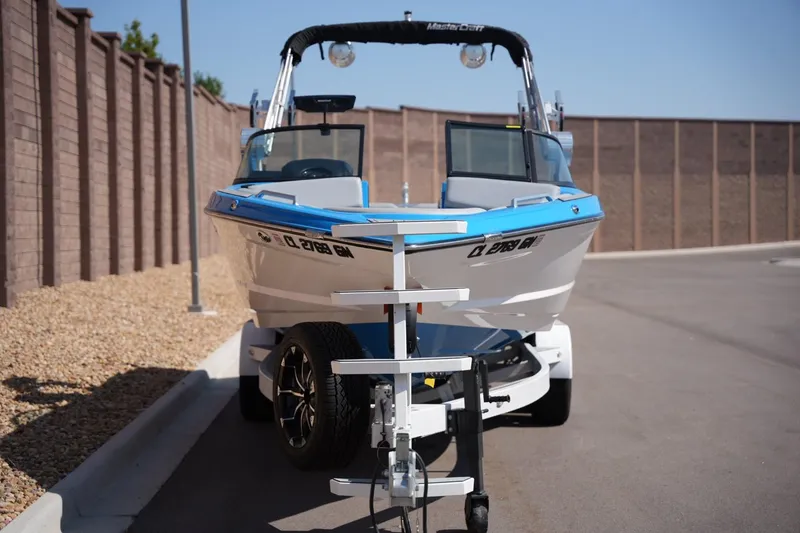 Slide: The Image of 2021 MasterCraft XT25 boat on trailer, parked on a paved road. - 6