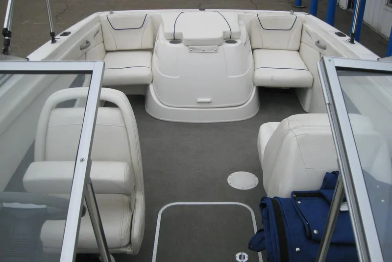 Slide: The Image of 2013 Bayliner 195 Discovery boat interior with white seating and carpeted floor. - 16