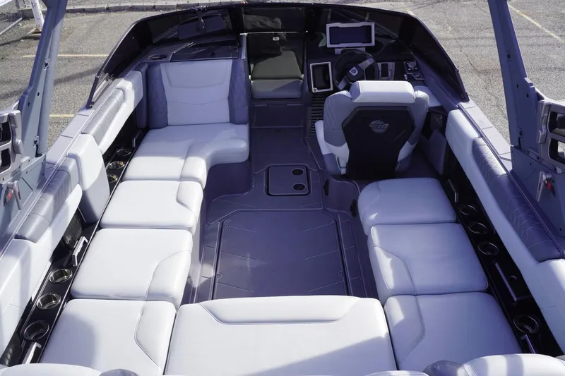 Slide: The Image of 2023 Malibu M220 boat interior with spacious seating and modern dashboard design. - 23