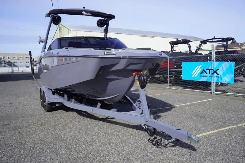 Slide: The Image of 2023 Malibu M220 boat on trailer in parking lot, ATX Surf Boats banner visible. - 3