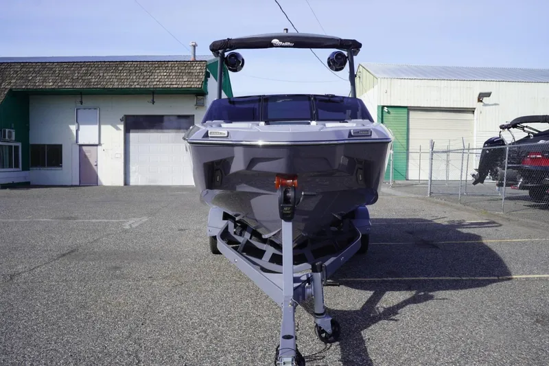 Slide: The Image of 2023 Malibu M220 boat parked in an industrial lot, front view. - 4