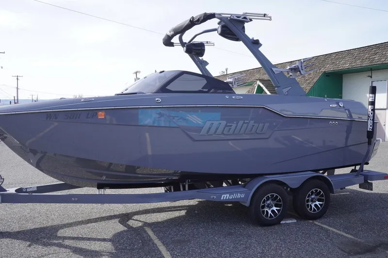 Slide: The Image of 2023 Malibu M220 boat on trailer, sleek design, parked outdoors. - 6