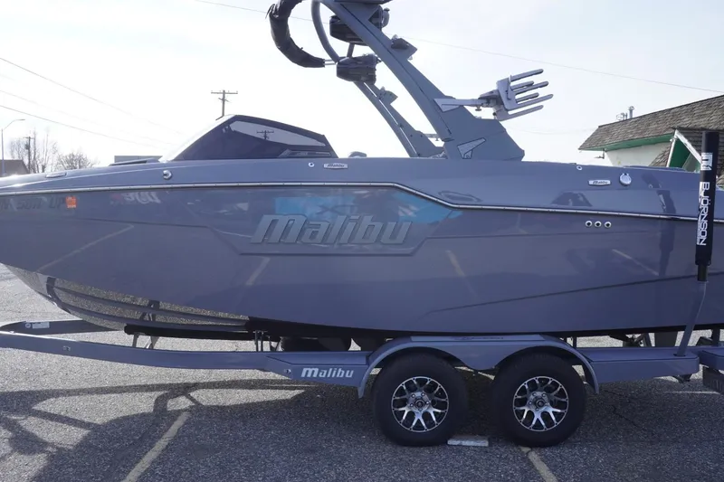 Slide: The Image of 2023 Malibu M220 boat on trailer, sleek design, gray color, parked outdoors. - 7