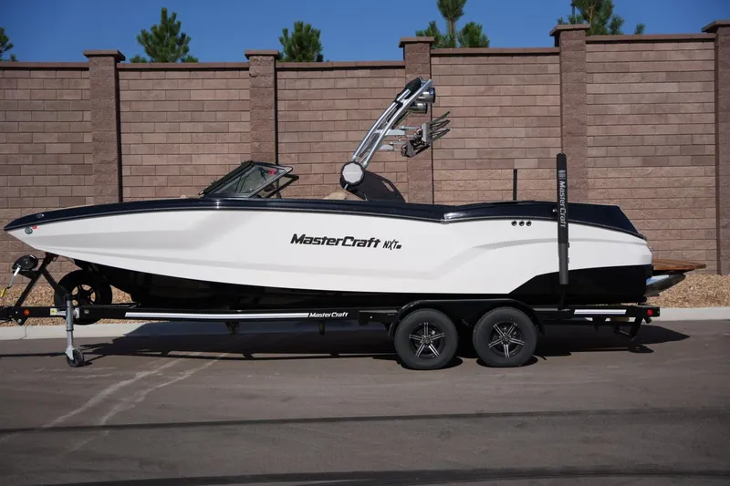 The Image of 2023 MasterCraft NXT24 boat on trailer, parked by brick wall. - 1