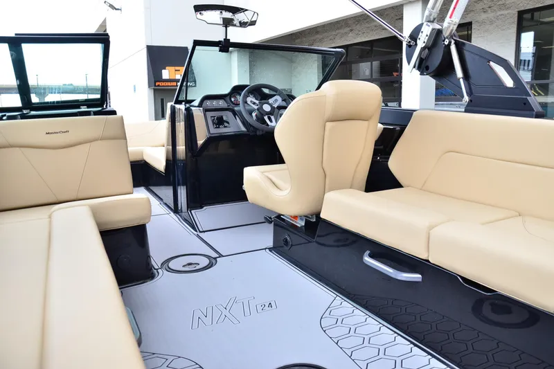 Slide: The Image of 2023 MasterCraft NXT24 boat interior with beige seating and modern dashboard design. - 13