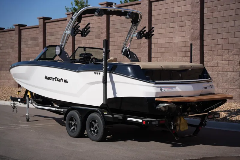 Slide: The Image of 2023 MasterCraft NXT24 boat on trailer, parked outdoors. - 2