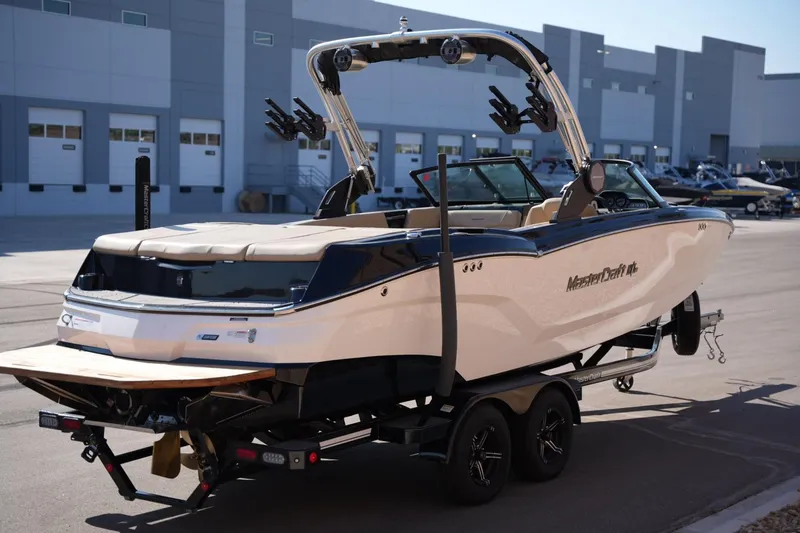 Slide: The Image of 2023 MasterCraft NXT24 boat on trailer, parked outside industrial building. - 4