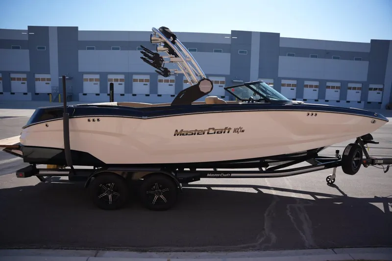 Slide: The Image of 2023 MasterCraft NXT24 boat on trailer, parked in industrial area. - 5