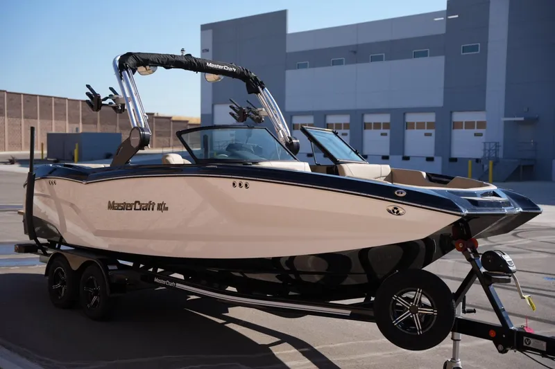 Slide: The Image of 2023 MasterCraft NXT24 boat on trailer in industrial setting. - 6