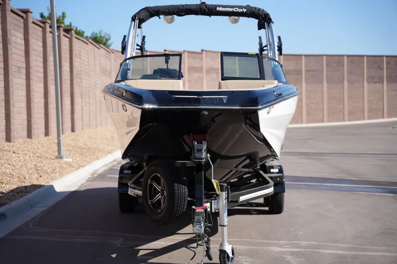 Slide: The Image of 2023 MasterCraft NXT24 boat on trailer, parked on a sunny street. - 7