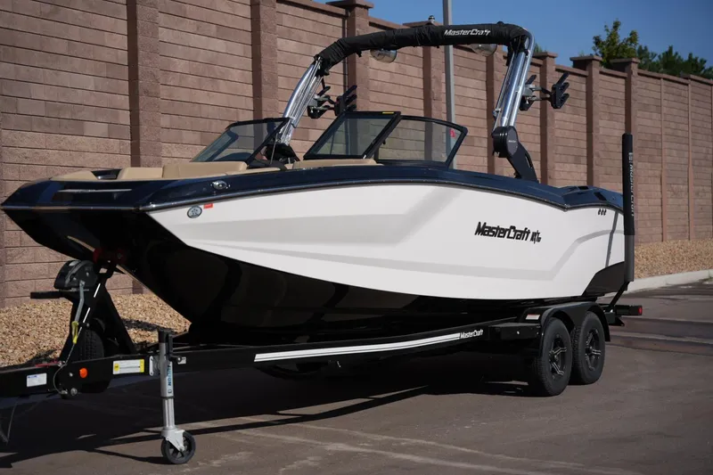 Slide: The Image of 2023 MasterCraft NXT24 boat on trailer, parked outdoors. - 8