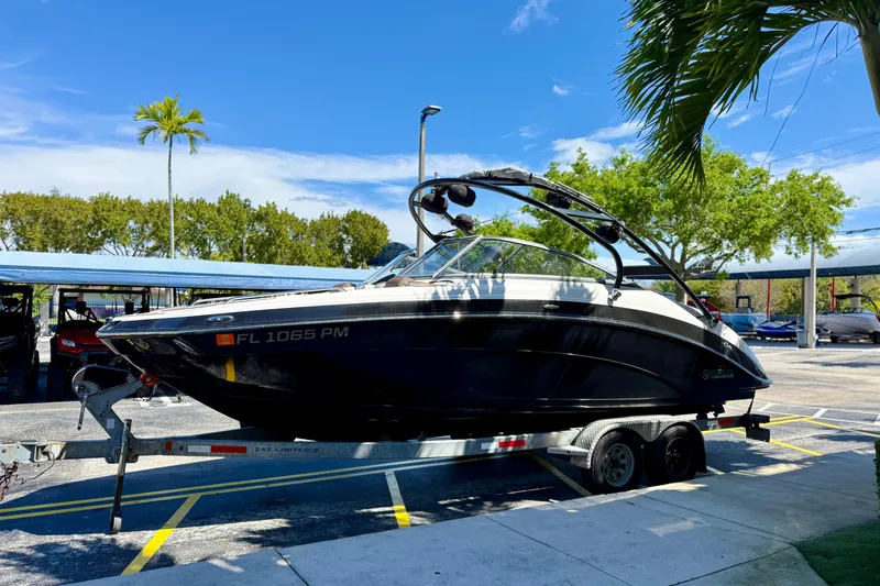 The Image of 2013 Yamaha Boats 242 Limited S on trailer, parked outdoors under clear blue sky. - 1