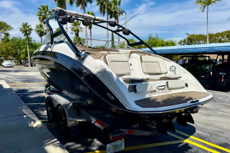 Slide: The Image of 2013 Yamaha Boats 242 Limited S on trailer, parked under palm trees. - 5