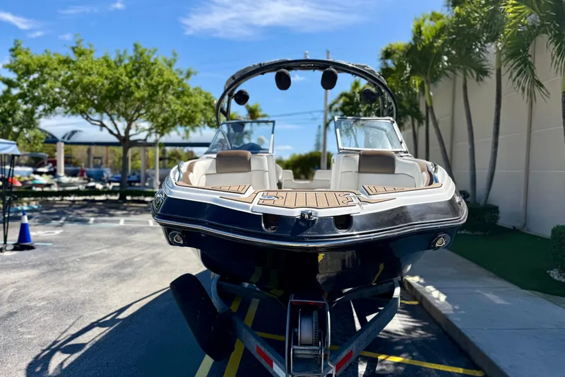 Slide: The Image of 2013 Yamaha Boats 242 Limited S on trailer, parked outdoors with trees in background. - 6