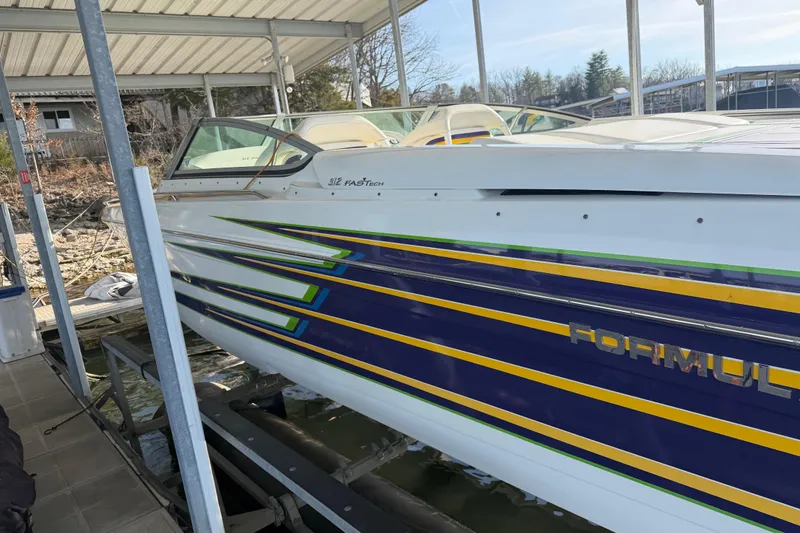Slide: The Image of 2001 Formula 312 FASTech boat with vibrant stripes docked under a canopy. - 15