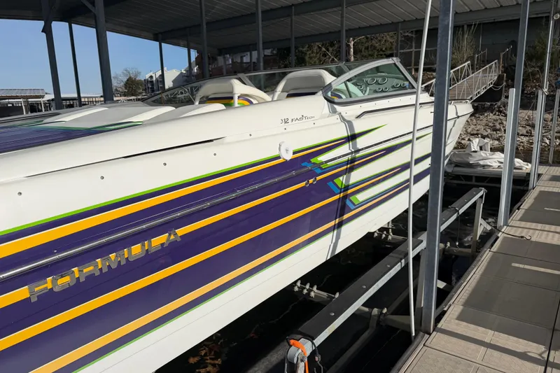 Slide: The Image of 2001 Formula 312 FASTech boat with vibrant stripes docked under a covered marina. - 4