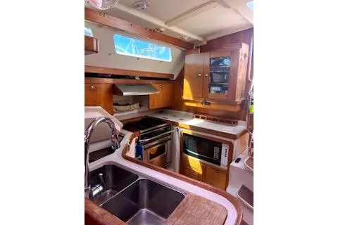 Slide: The Image of 2006 Catalina 400 MkII yacht kitchen with modern appliances and wooden cabinetry. - 28