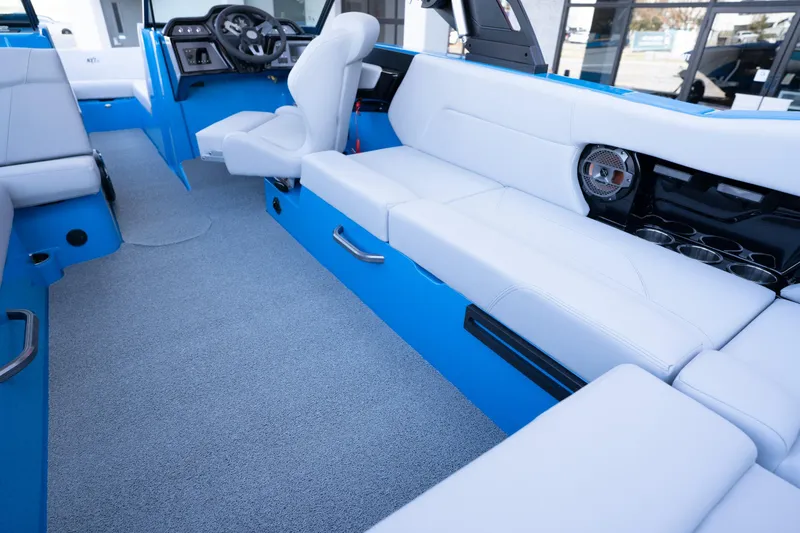 Slide: The Image of 2022 MasterCraft NXT24 boat interior with blue and white seating, modern dashboard, and speaker system. - 11