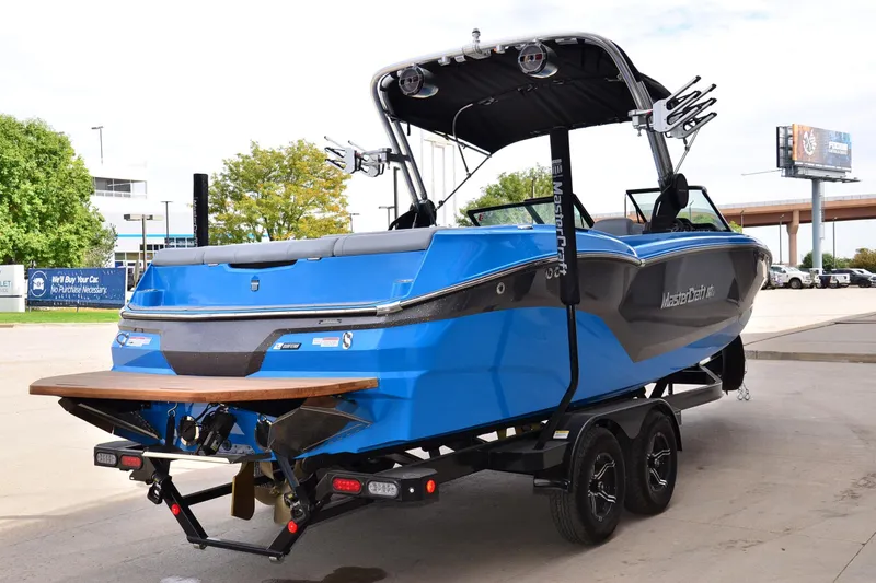 Slide: The Image of 2022 MasterCraft NXT24 boat in blue on trailer, parked outdoors. - 3
