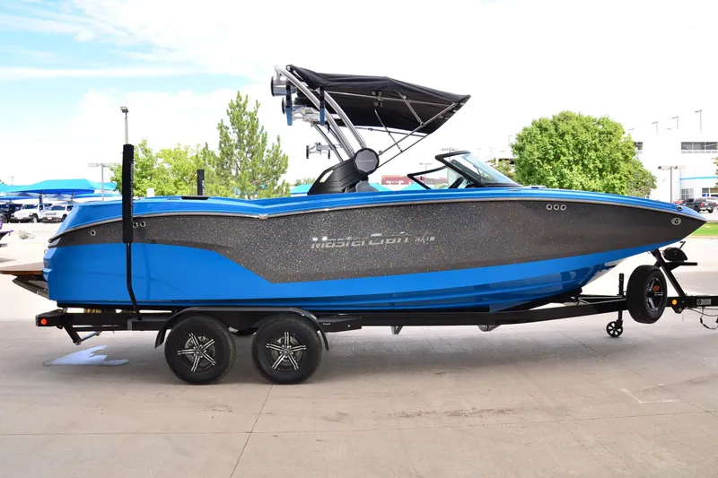 Slide: The Image of 2022 MasterCraft NXT24 boat in blue and black on a trailer, parked outdoors. - 4