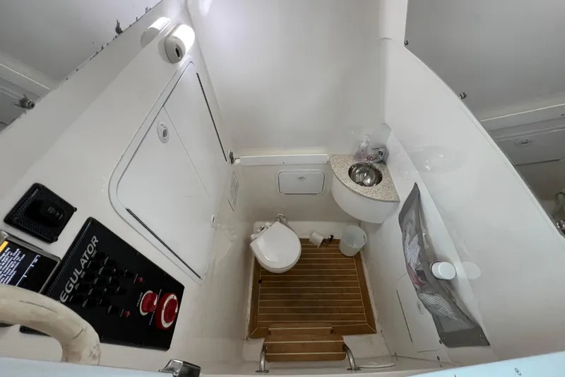 Slide: The Image of 2018 Regulator 28 boat bathroom with sink, toilet, and control panel. - 21