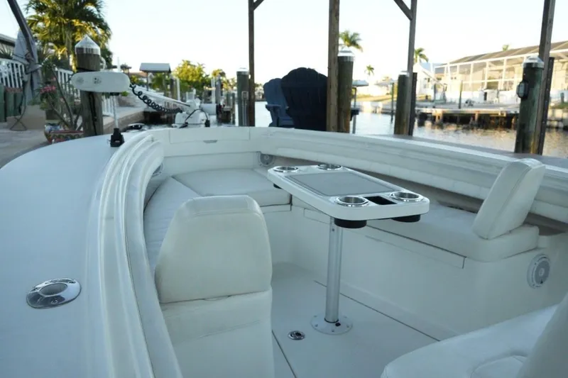 Slide: The Image of 2018 Regulator 28 boat interior with seating and table, docked by waterfront homes. - 26