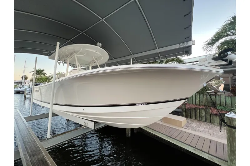 Slide: The Image of 2018 Regulator 28 boat on lift under canopy, docked near water. - 4