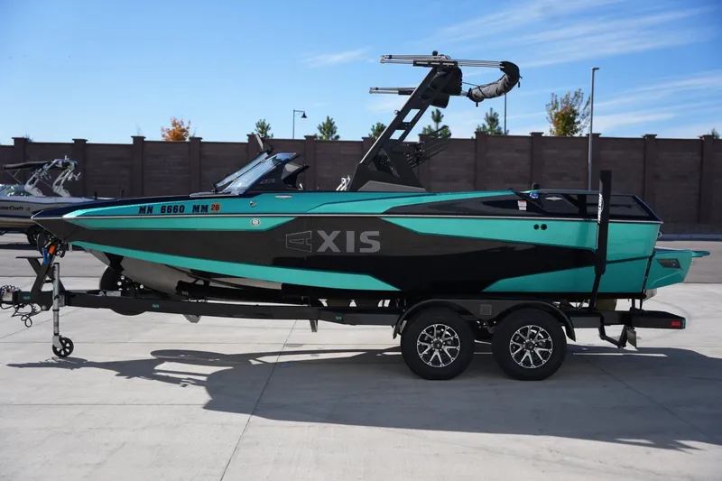 The Image of 2023 Axis A20 boat on trailer, teal and black design, parked outdoors. - 1