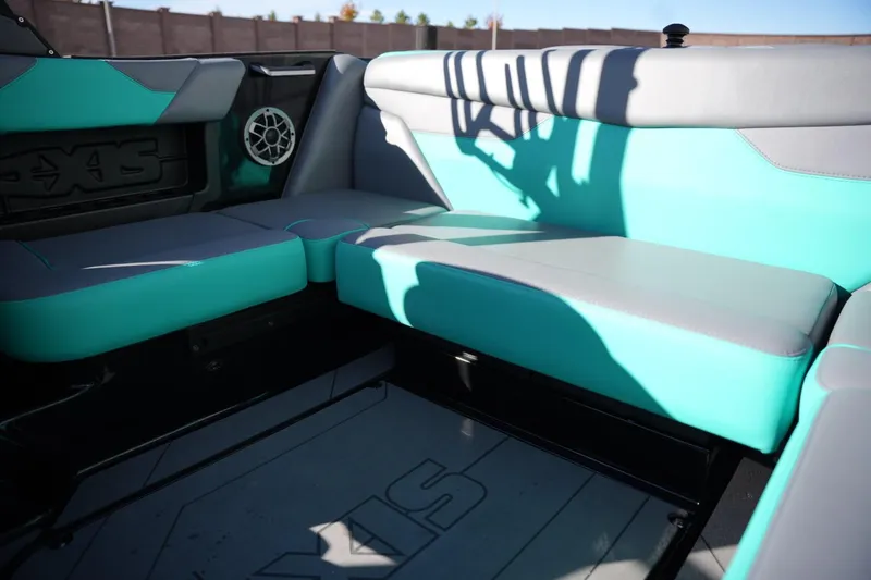 Slide: The Image of 2023 Axis A20 boat interior with teal and gray seating, featuring a speaker and logo. - 15