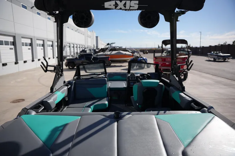 Slide: The Image of 2023 Axis A20 boat interior with teal and gray seating, parked outdoors. - 20