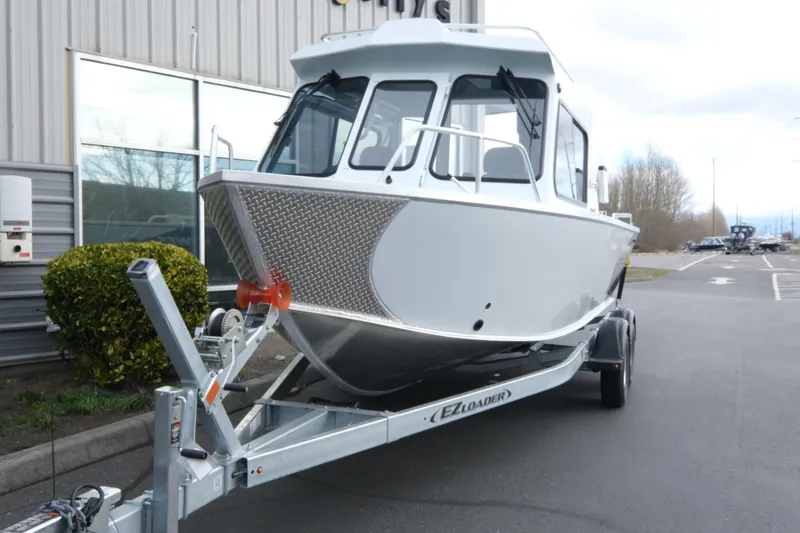 Slide: The Image of 2026 Hewescraft 210 Sea Runner ET Hardtop on trailer, parked outside a building. - 3