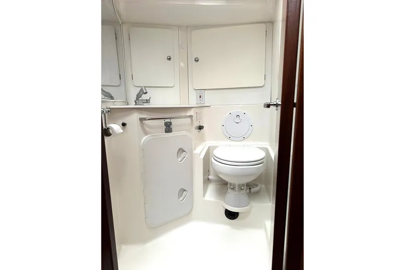 Slide: The Image of Bathroom interior of a 2003 Bavaria 44 yacht, featuring a compact toilet and storage cabinets. - 17