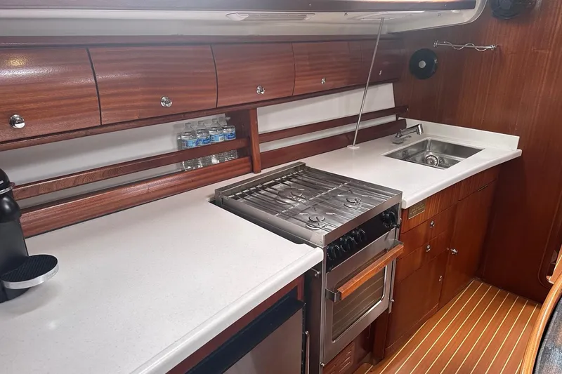 Slide: The Image of Luxurious 2003 Bavaria 44 yacht kitchen with stove, sink, and wooden cabinetry. - 21