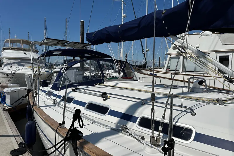 Slide: The Image of 2003 Bavaria 44 sailboat docked at marina, surrounded by other boats under clear blue sky. - 4