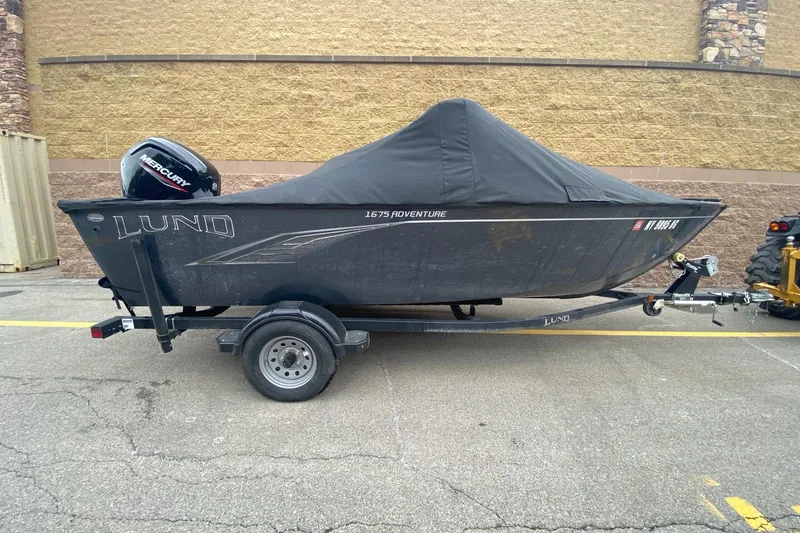 Slide: The Image of 2022 Lund 1675 Adventure Sport boat with cover on trailer, parked outdoors. - 11